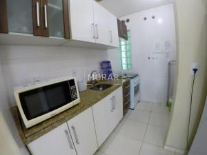 cocina blanca con microondas y fregadero en Apartamentos em Bombas, en Bombinhas