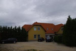 uma casa com dois carros estacionados em frente em Hóvirág Panzió em Porva