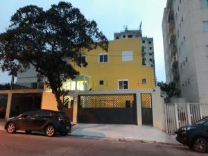 ein schwarzes Auto, das vor einem gelben Gebäude parkt in der Unterkunft Hotel Casa Ocarina in São Paulo