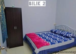 a bedroom with a bed with a blue and white comforter at Syaqisya Homestay in Seri Manjung