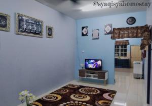a living room with a tv and a blue wall at Syaqisya Homestay in Seri Manjung