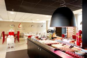 a restaurant with a buffet line with red chairs at Campanile Paris 19 - La Villette in Paris