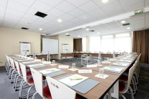 une grande salle de conférence avec de longues tables et chaises dans l'établissement Campanile Paris 19 - La Villette, à Paris