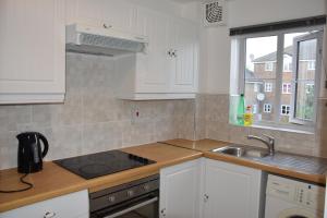 a kitchen with white cabinets and a sink and a window at 1 Bedroom Apartment Ponders End in London