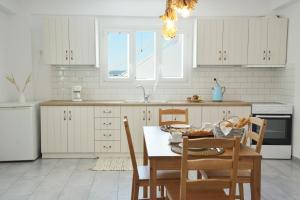 a kitchen with white cabinets and a table and chairs at La casa de Verde in Péran Triovasálos