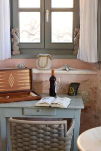 伊茲拉的住宿－On The Port Mansion Studio 2 Hydra，一张桌子,上面放着一本书和一瓶葡萄酒