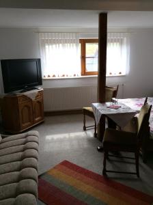 a living room with a table and a tv at Landhotel Quelle in Heidersdorf