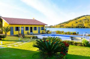 a yellow house with a swimming pool next to a lake at TuTu TonTo Acomodações e Lazer in Capitólio