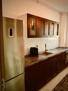 a kitchen with wooden cabinets and a stainless steel refrigerator at Music Apartment in Otopenii de Jos