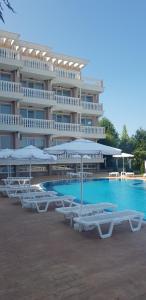 a hotel with chairs and umbrellas next to a swimming pool at Perla Del Mar Aparthotel in Lozenets