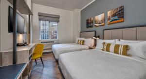 Una habitación de hotel con dos camas, un escritorio y un televisor. en Citadines Connect Fifth Avenue New York, en Nueva York
