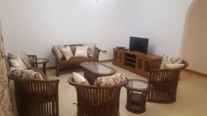 a living room with wicker chairs and a tv at Anse Royale Bay View Apartments in Mahe
