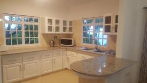 a kitchen with white cabinets and a granite counter top at Anse Royale Bay View Apartments in Mahe