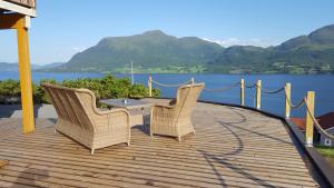 2 sillas y una mesa en una terraza de madera junto al agua en Kvernesfjorden Apartments, en Averoy