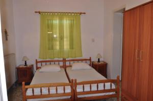 a bedroom with two beds and a green curtain at Aegina town, summer house in Egina