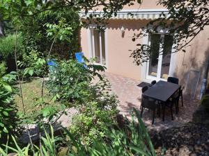 a patio with a table and chairs in a house at Appartement dans propriété calme en pleine nature in Charbonnières-les-Bains