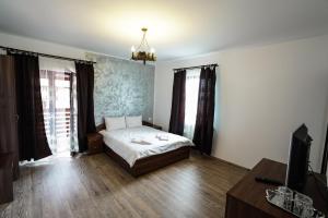 a bedroom with a bed and a tv in it at Pensiunea Trei Lalele in Moisei +87 photos