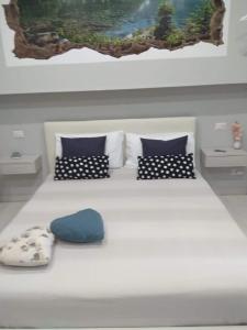 Elle comprend un grand lit blanc avec des oreillers bleus et un tableau. dans l'établissement Cataleya, à Catane