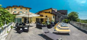 a patio with chairs and an umbrella and a building at Hotel Borgo dei Poeti Romantik Wellness & SPA in Manerba del Garda