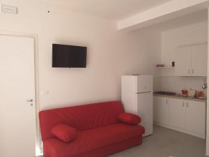 a living room with a red couch and a refrigerator at La Bussola in Porto Cesareo
