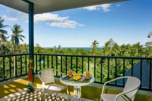 balcón con mesa, sillas y vistas al océano en Butterfly Garden Villa, en Laem Set Beach