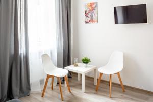 利維夫的住宿－Frederic apartments，客房内的2把白色椅子和1张白色桌子