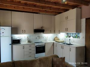 a kitchen with white cabinets and white appliances at Villa AMIA in Áyios Spirídhon