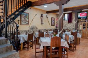 a restaurant with tables and chairs and a staircase at Hostal Tribal in Puebla de Sanabria