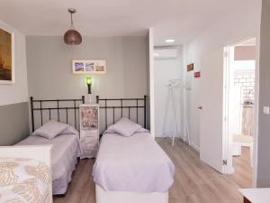 twee bedden in een kamer met witte muren en houten vloeren bij Lolita's house torre del oro in Sevilla