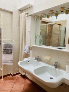 bagno con lavandino bianco e specchio di Villa Panoramica a Lavena Ponte Tresa