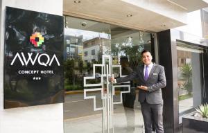 a man in a suit standing in front of a glass door at Awqa Concept Hotel in Trujillo