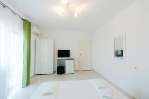 a white room with a bed and a television at Casa Erty in Eforie Nord