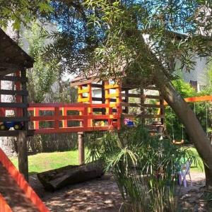 a playground with a red fence and a tree at Cabañas Marjumi in Mar de las Pampas