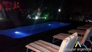 a swimming pool with two wooden benches next to it at Cabañas Marjumi in Mar de las Pampas
