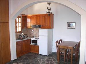 a kitchen with a table and a white refrigerator at Niriides Studios in Armenistis