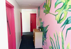 a hallway with a pink wall with plants painted on it at Trek Global Backpackers in Wellington