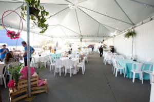a white tent with white tables and chairs and people at Pousada Beer In Night in Lençóis Paulista