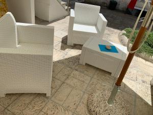 um pátio com 2 cadeiras e uma mesa com um guarda-sol em Villa Azzurra Sct em Santa Cesarea Terme