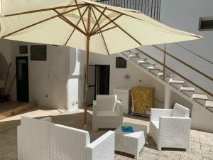 um pátio com um guarda-sol, cadeiras e escadas em Villa Azzurra Sct em Santa Cesarea Terme
