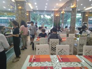 a group of people sitting at tables in a restaurant at DREAM HOTEL Bắc Ninh in Hòa Ðình