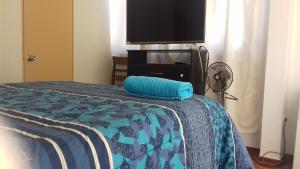 a bed with a blue comforter and a flat screen tv at Casa Blanca Hospedaje in Mejillones