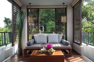 a porch with a couch and a table at Anantara Lawana Koh Samui Resort in Chaweng