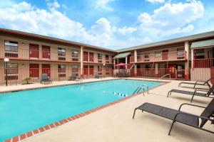 une piscine en face d'un hôtel avec bancs dans l'établissement Super 8 by Wyndham Malvern, à Malvern