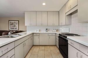 a kitchen with white cabinets and a sink and a stove at Travelodge by Wyndham Lake Havasu in Lake Havasu City