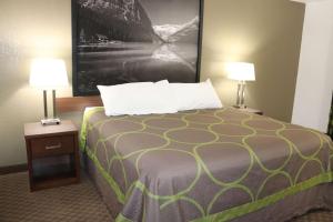 a large bed in a hotel room with two lamps at Super 8 by Wyndham Hinton in Hinton