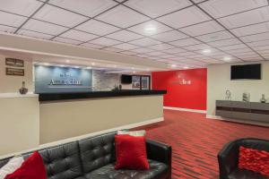 a waiting room with a leather couch and a tv at AmericInn by Wyndham Janesville in Janesville