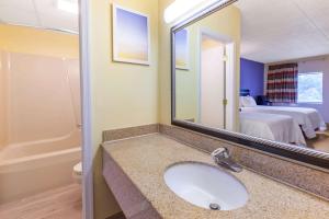 a bathroom with a sink and a mirror and a bed at Days Inn by Wyndham Grantville in Grantville