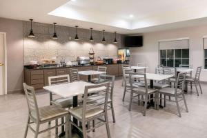 a dining room with tables and chairs and a kitchen at La Quinta by Wyndham Fredericksburg in Fredericksburg