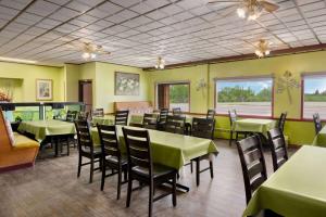 Travelodge by Wyndham Dawson Creek في داوسون كريك: غرفة طعام مع طاولات وكراسي خضراء