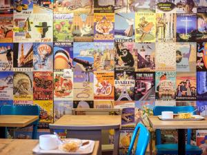 a restaurant with tables and a wall covered in posters at hotelF1 Laval in Chang&eacute;